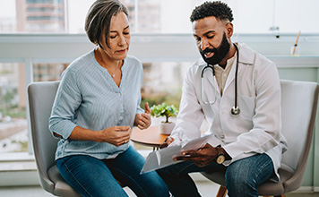 A doctor sits and discusses care with a patient. 