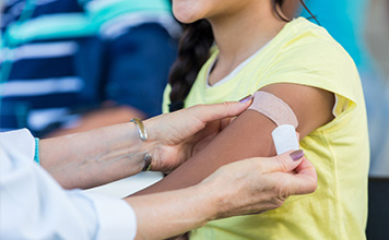 A health care provider puts a band aid on a person's arm 