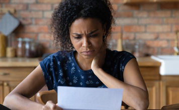 A woman holds a document with a confused look on her face. 