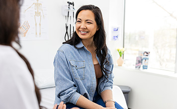 A woman smiles as she talks with her provider. 