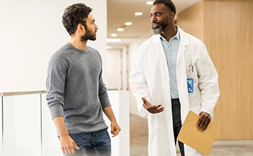 A doctor and patient walk together while talking.