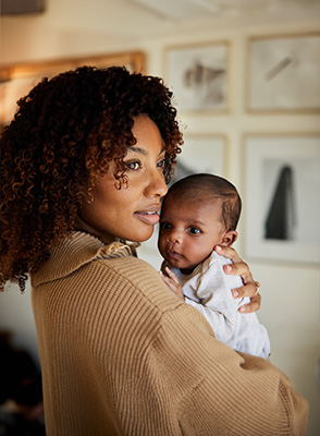 woman holds baby while talking on phone