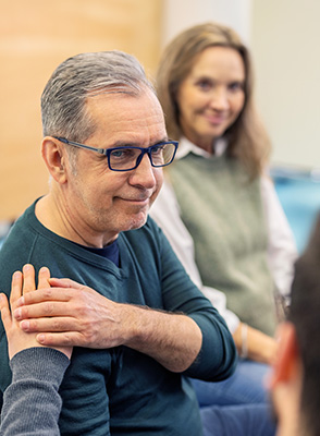 A man getting emotional support other participants during group therapy session