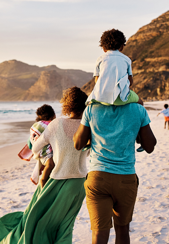 A family walks along a beach while on vacation.