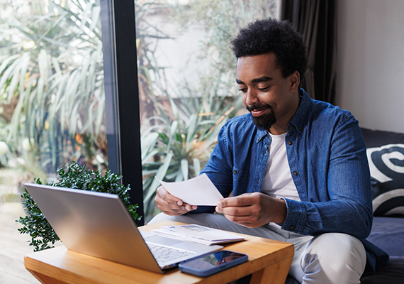 Young man sitting at a laptop paying his BCBSM bills.