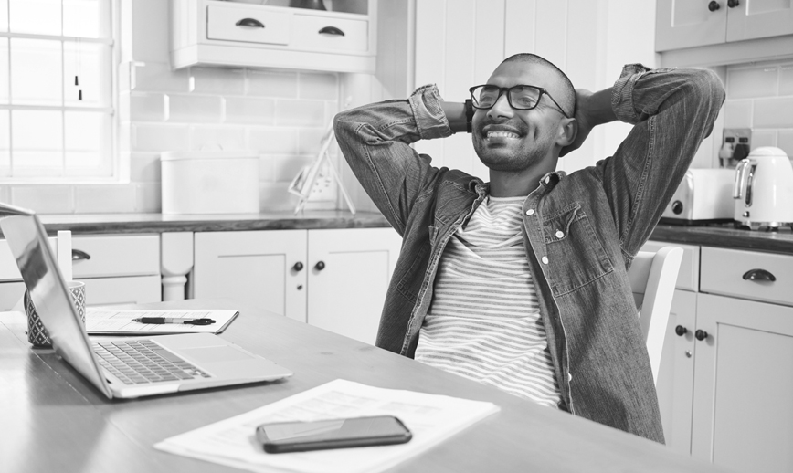 Young man sitting at kitchen table paying his BCBSM bills.