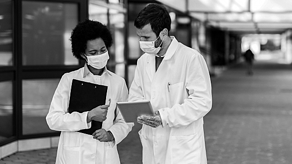 Two doctors dicuss documents with masks on.