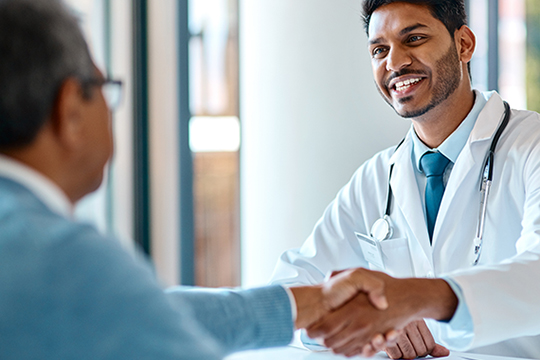 A doctor shakes hands with a patient.