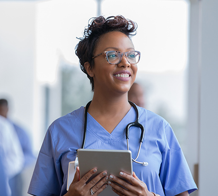 A health care provider holding a tablet and wearing a tethescope.