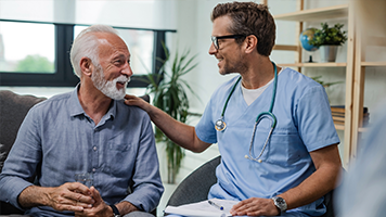 A man smiles while talking with his doctor. They're both smiling, so it looks like good news.