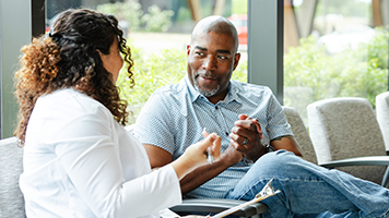 A seated man and woman having a lighthearted discussion