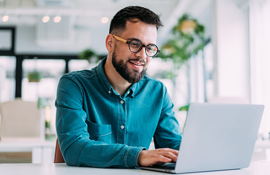 A man sitting at a desktop, smiling