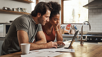 A couple stares intently at a laptop screen