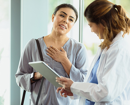Two health care professionals have a discussion while looking at a tablet.