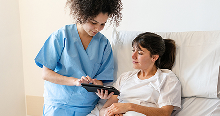 A doctor shows her patient some information on a tablet.