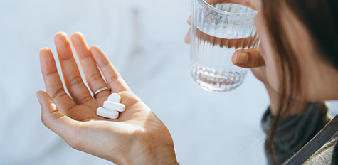 Person holding prescription pills and a glass of water