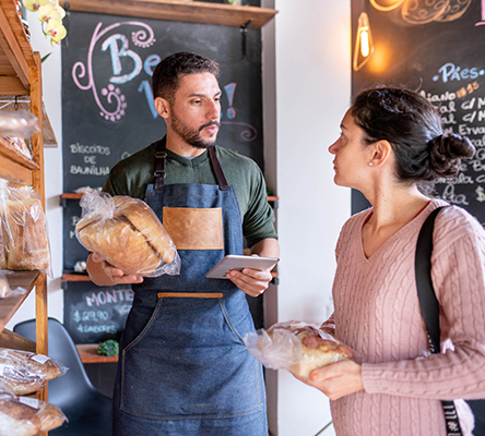 A female customer buying bread from a male store worker