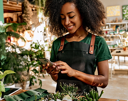 woman in a flower shop lookinf at her mobile phone