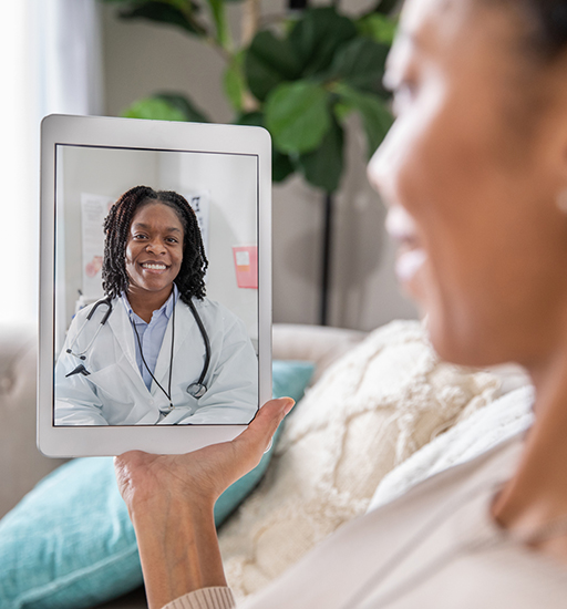 A smiling woman speaks to a medical professional on her tablet