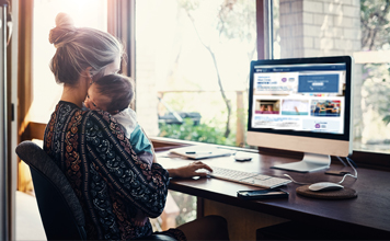 A woman holds her baby while looking at her plan