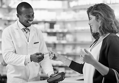 A pharmacist laughs with a happy customer. 
