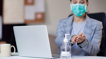 A woman uses hand sanitizer while learning online