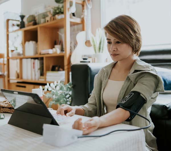 Woman using blood pressure monitor device