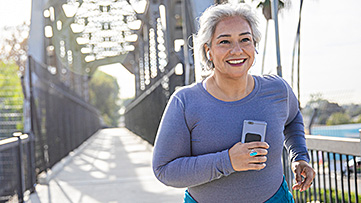 A woman happily walks across a bridge