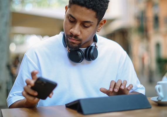 A young man wearing headphones looks at his mobile device