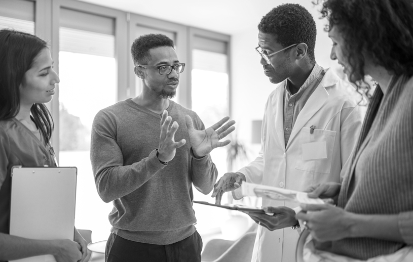 Three professionals have a conversation in a health care setting