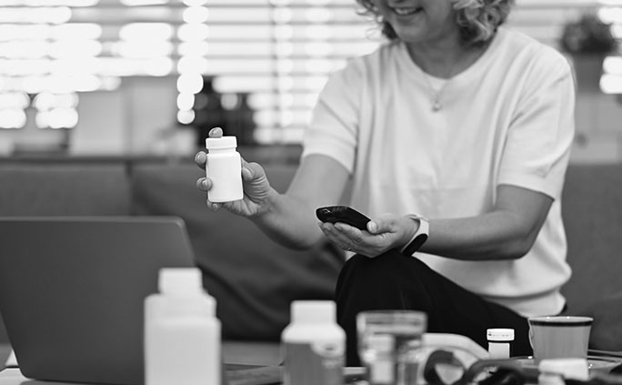 A woman holds a blood glucose meter and a prescription bottle