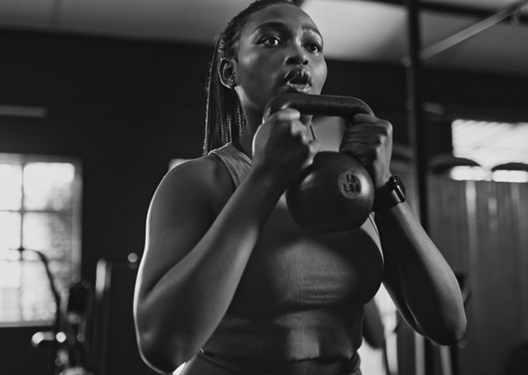 A woman lifts a weight at the gym. 