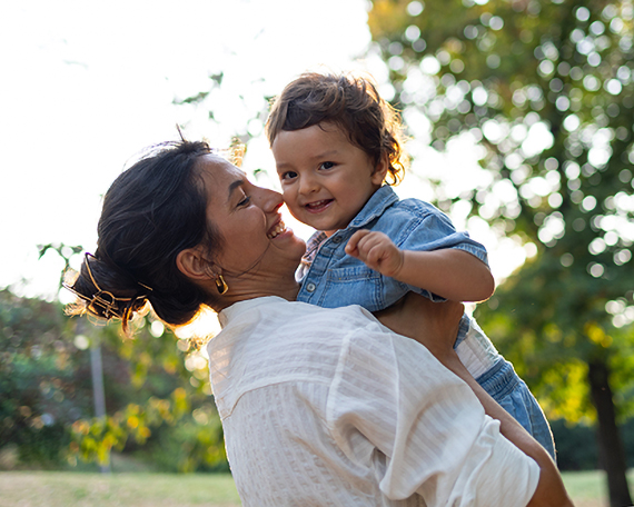 A smiling mother holding a smiling toddler