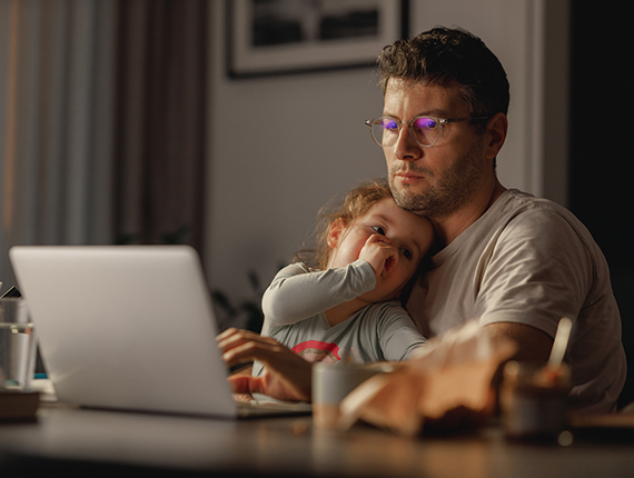 Person working on computer with a toddler on his lap