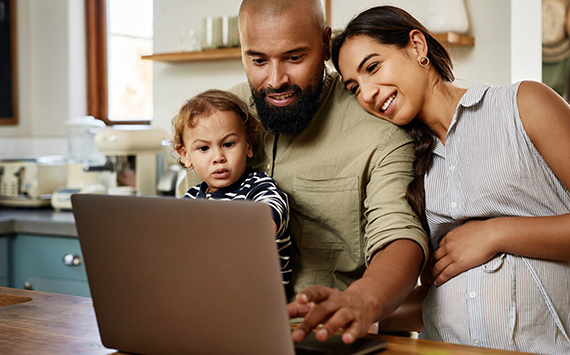 A mother, father and child looking at a laptop