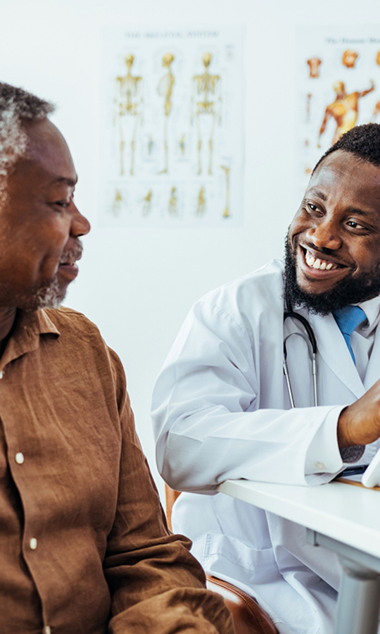 A doctor smiles while talking to his patient.