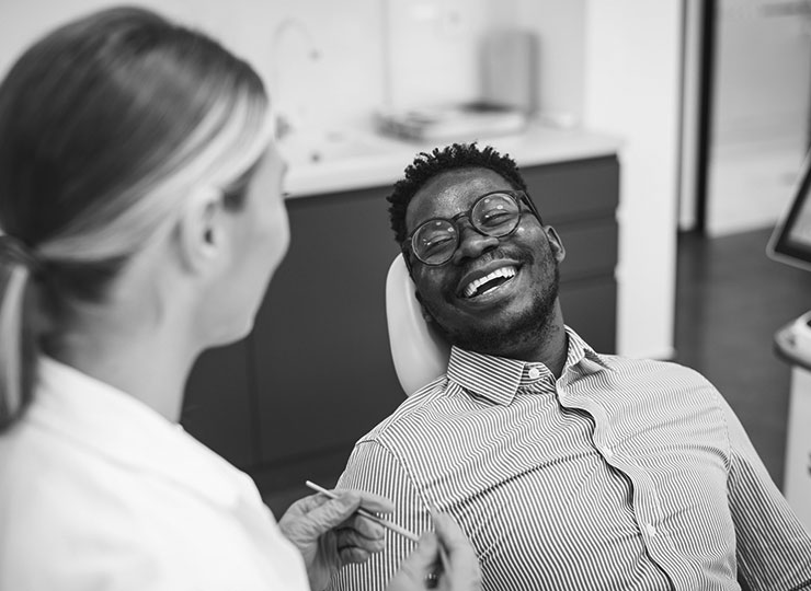 Dental professional holds instrument while talking with smiling patient