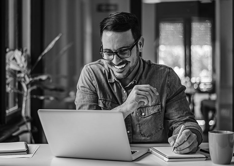 A man smiles as he takes notes about his health insurance. 