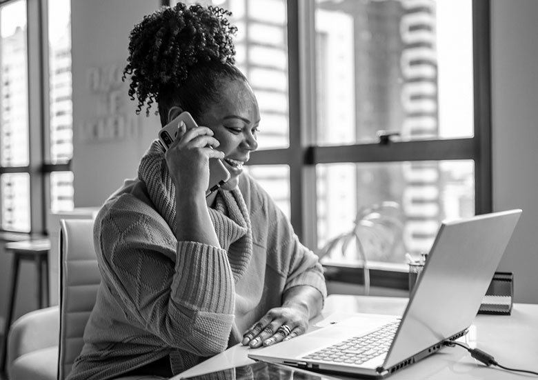 A woman smiles as she talks on the phone. 