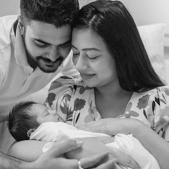 A man and a woman hold a newborn baby.