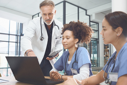 Medical professionals look at a laptop screen together.
