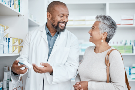  A pharmacist and woman smile while talking about a medication