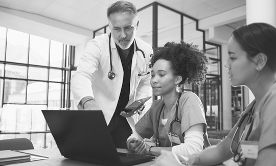 Medical professionals look at a laptop screen together.