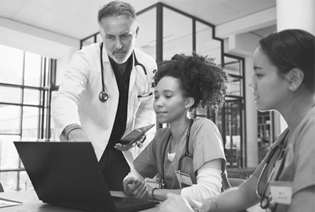 Medical professionals look at a laptop screen together.