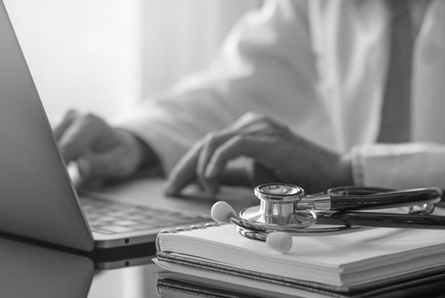 A doctor enters in client information on their laptop. 