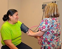 A nurse takes a woman's blood pressure